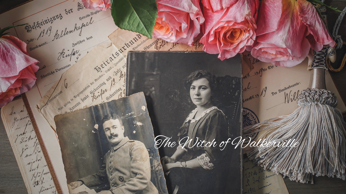 Pink roses on top of some antique papers and forms. There are two old photos of a man and woman on top of the papers. 