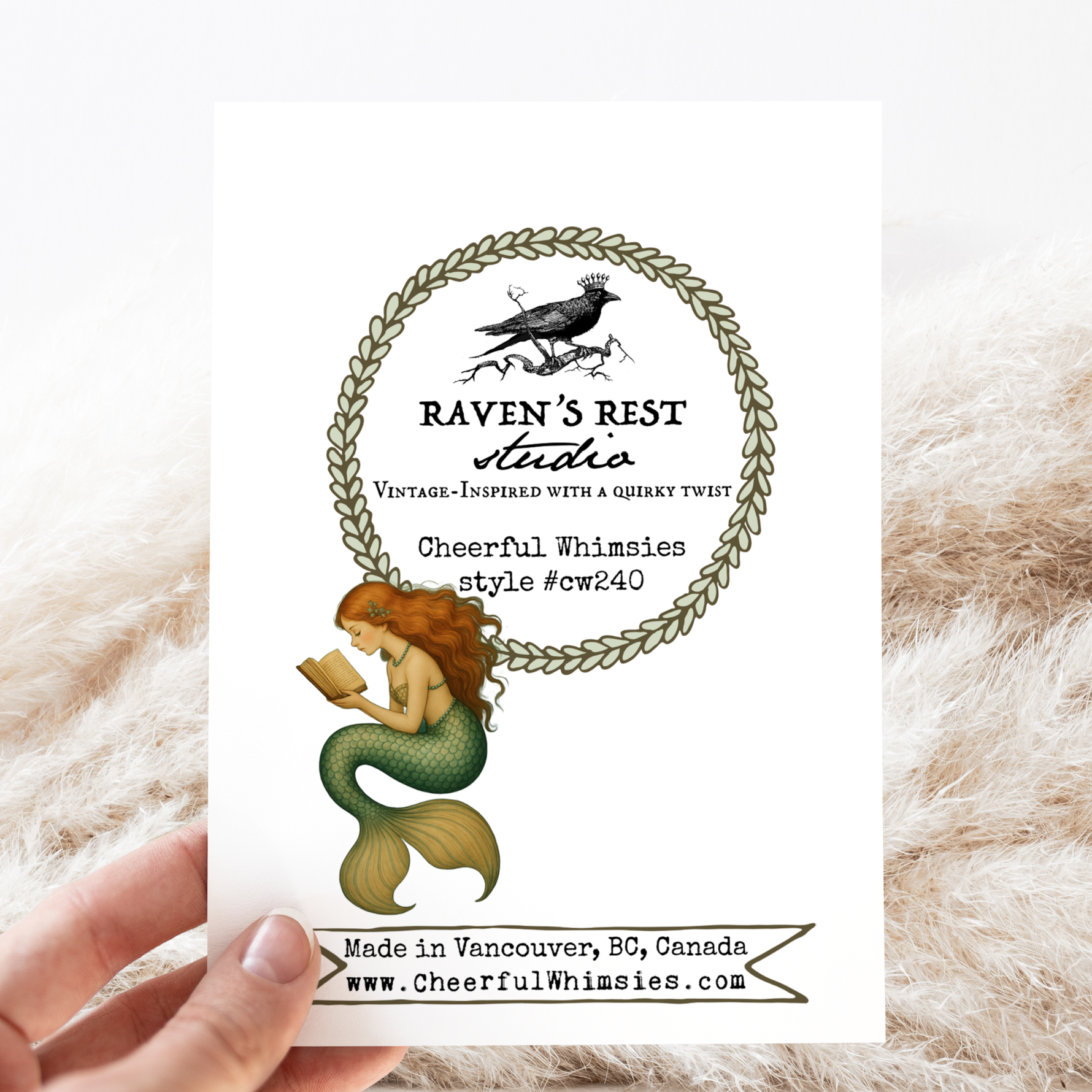 Card with mermaid illustration and 'Raven's Rest Studio' branding on a textured surface.
