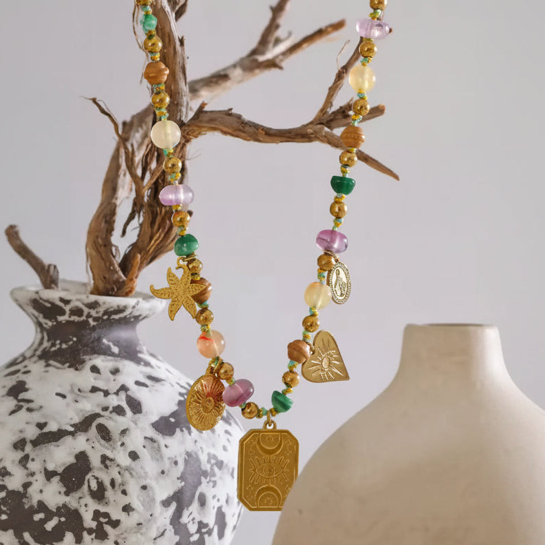 Colorful beaded necklace with charms on a neutral background