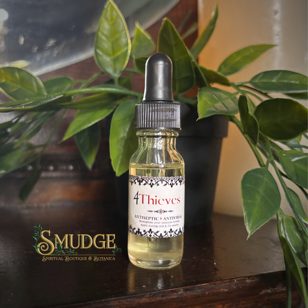 Bottle of '4 Thieves' oil with a dropper on a wooden surface with green plants in the background.