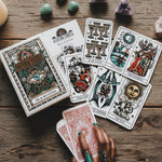 Collection of tarot cards on a white surface with a hand holding a card.