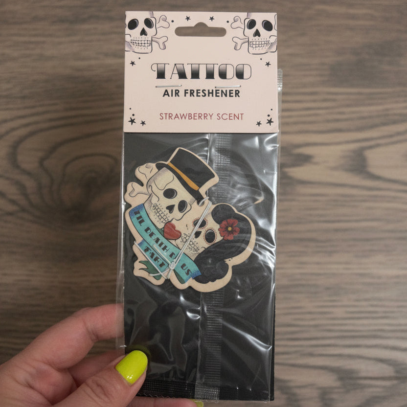 Tattoo-themed air freshener with strawberry scent packaging held by a hand.