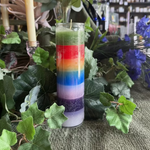 Colorful layered candle with green leaves and candles in the background