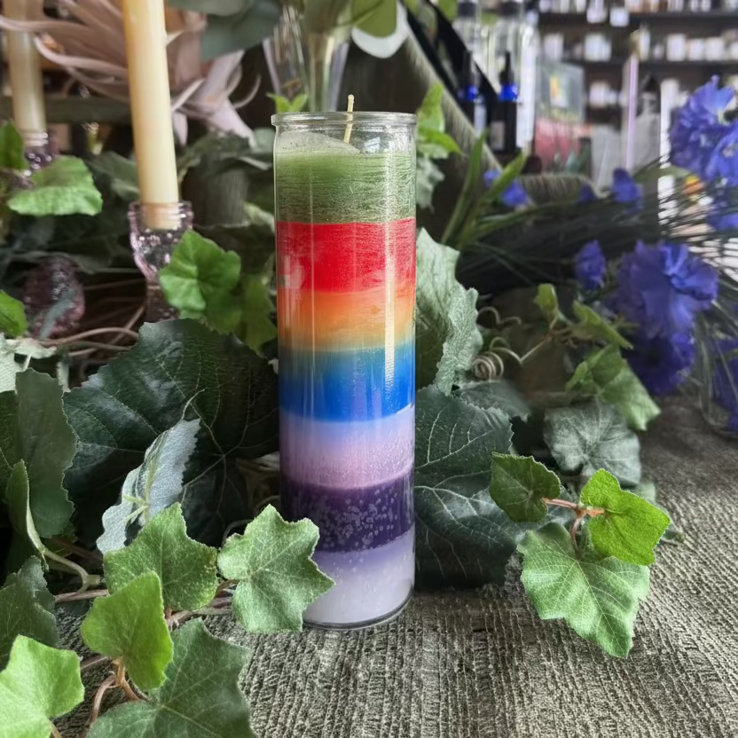 Colorful layered candle with green leaves and candles in the background