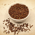 White bowl filled with dried seeds on a textured surface