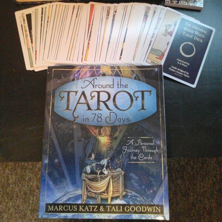 Collection of tarot cards, book, and dice on a dark surface