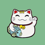 Maneki-neko cat charm held in a hand against a pink background