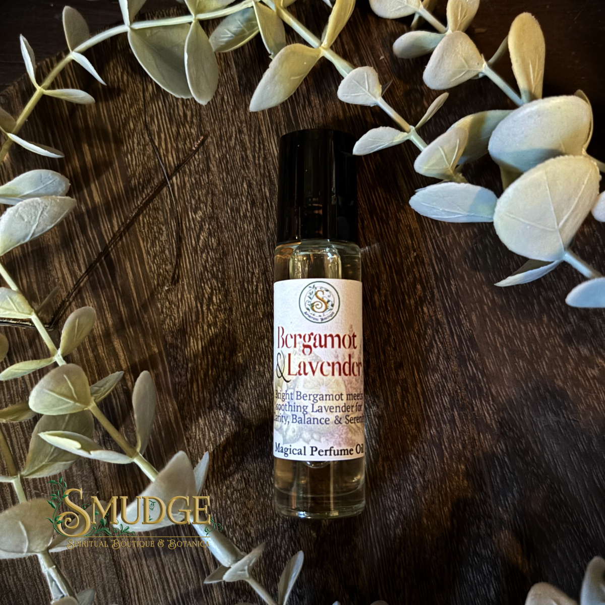 Bottle of Bergamot & Lavender perfume oil on a wooden surface with eucalyptus leaves.