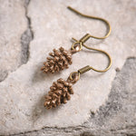 Bronze pine cone earrings on a stone surface