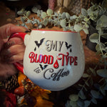 A hand holding a coffee mug hat says My Blood type is Coffee. 