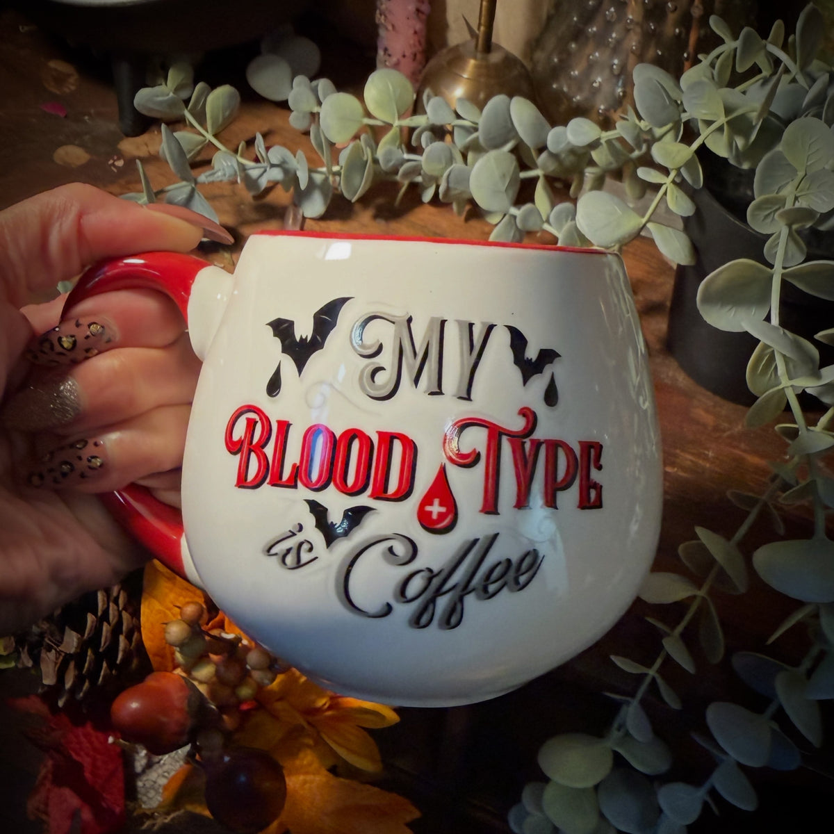 A hand holding a coffee mug hat says My Blood type is Coffee. 