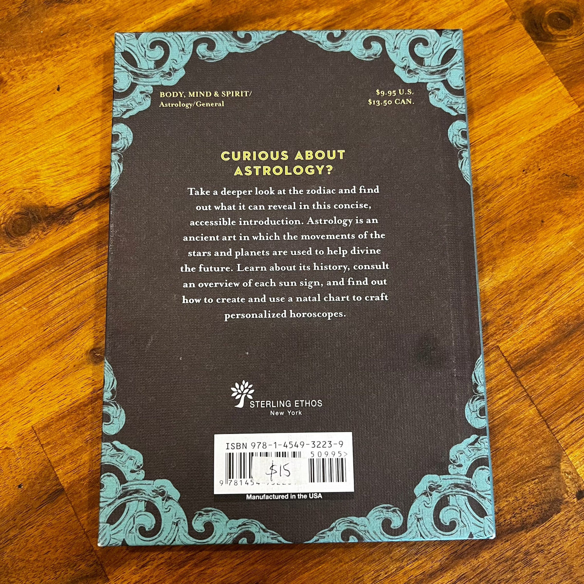 Back cover of a book on astrology with decorative elements on a wooden surface