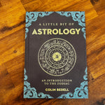 Book titled 'A Little Bit of Astrology' by Colin Bedell on a wooden surface