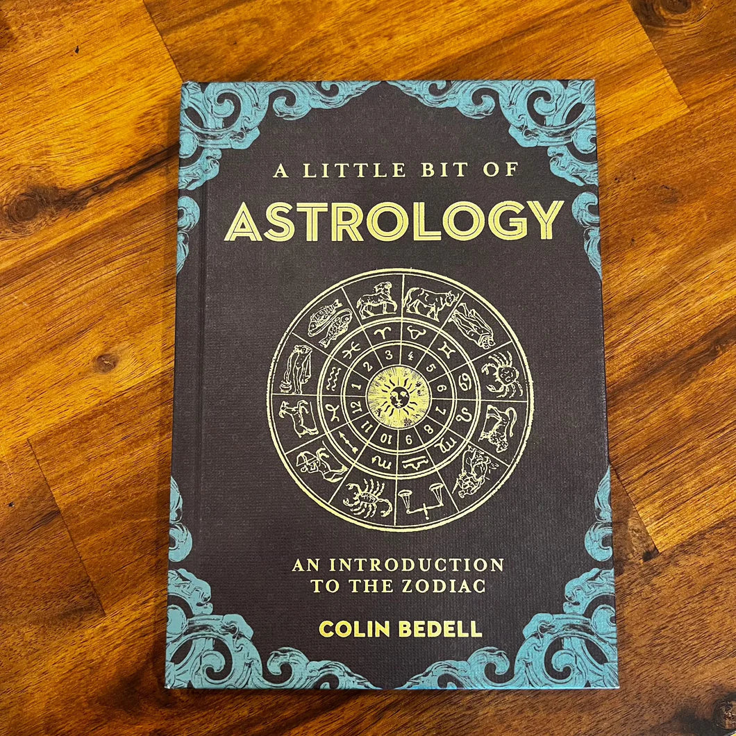 Book titled 'A Little Bit of Astrology' by Colin Bedell on a wooden surface