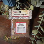 Auntie M's Ghost incense Powder packaging with a label on a wooden surface with eucalyptus leaves.