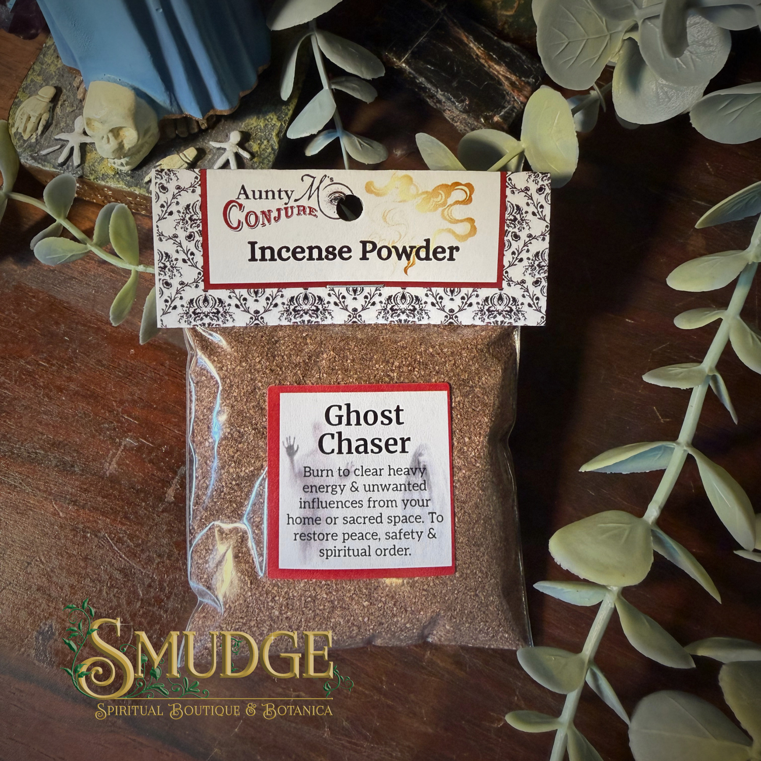 Auntie M's Ghost incense Powder packaging with a label on a wooden surface with eucalyptus leaves.