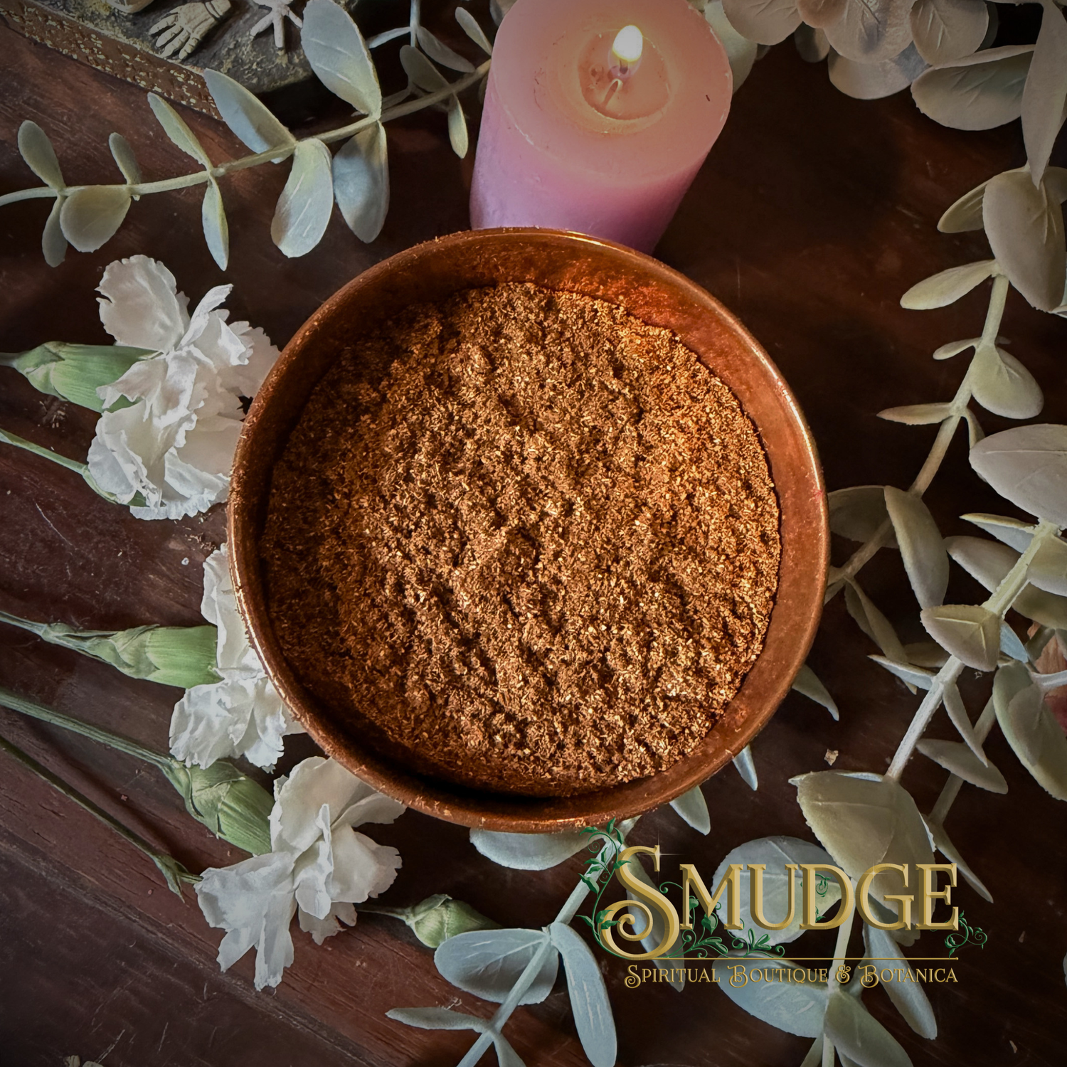 Wooden bowl with brown incense powder on a decorative surface with flowers and a candle, featuring the brand 'Smudge'.