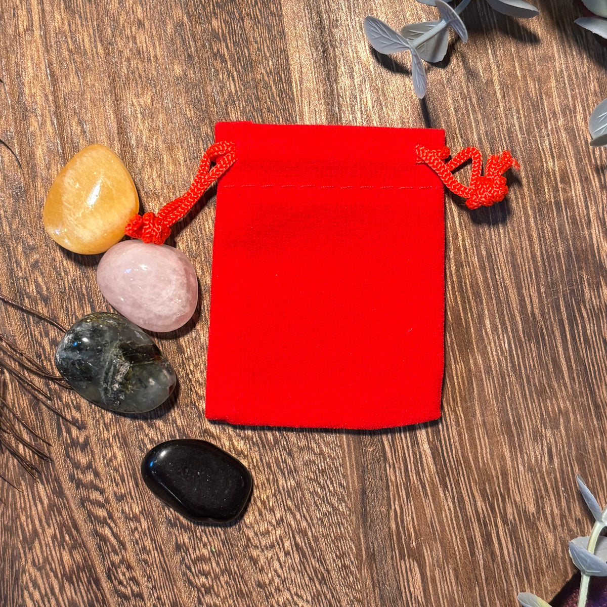 Red drawstring pouch on a wooden surface with stones around it