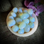 Round white stones in a bowl on a textured fabric background with pink flowers.