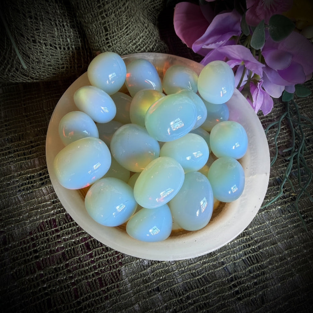 Round white stones in a bowl on a textured fabric background with pink flowers.
