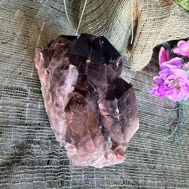 Crystal on a textured surface with flowers and a carrot in the background