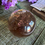 Crystal ball on a textured surface with purple flowers and a card in the background