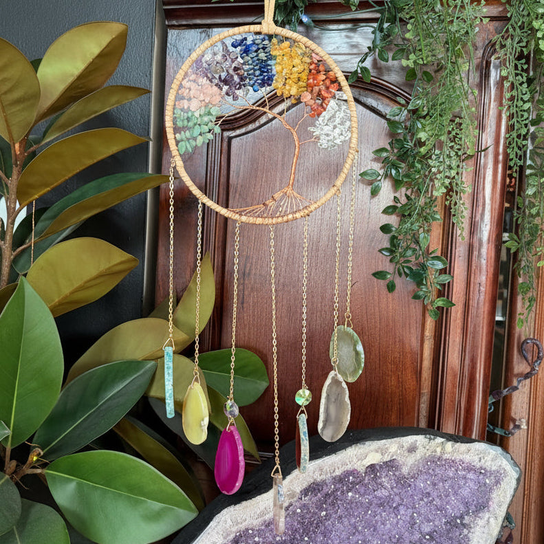 Collection of necklaces on a wooden surface with plants and crystals in the background