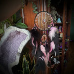 Close-up of a hand holding a decorative item on a wooden surface with plants and other objects in the background.