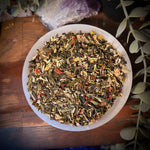 Herbal tea  flu fighter in a white bowl on a wooden surface with plants and crystals in the background