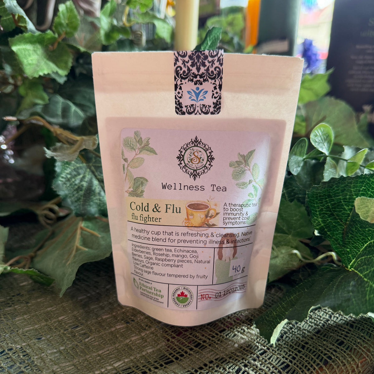 Wellness tea package with a decorative straw on a textured surface with greenery in the background