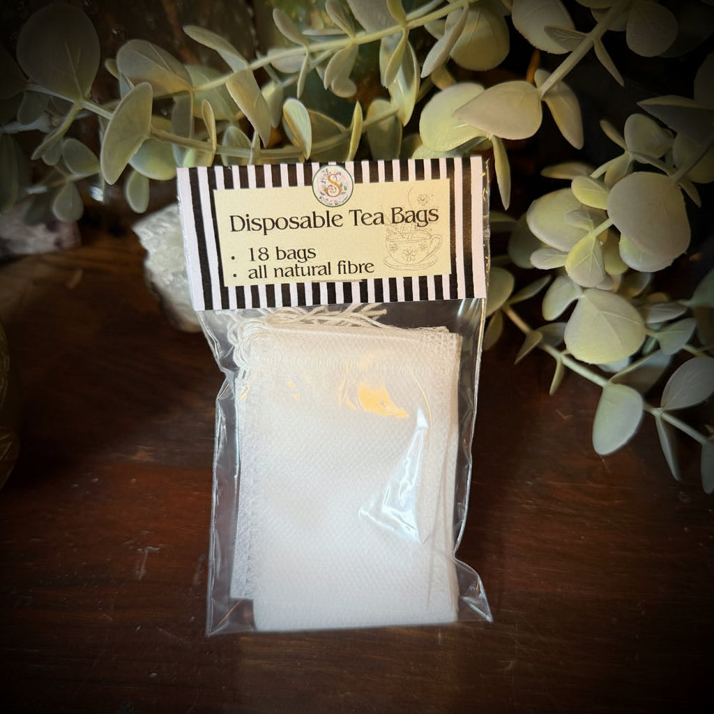 Disposable tea bags in a clear package on a wooden surface with green leaves.