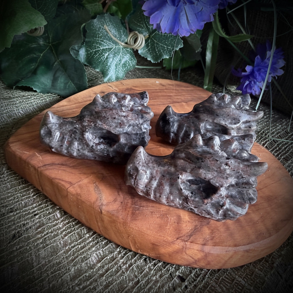 Decorative stone sculpture on a wooden base with purple flowers and greenery.