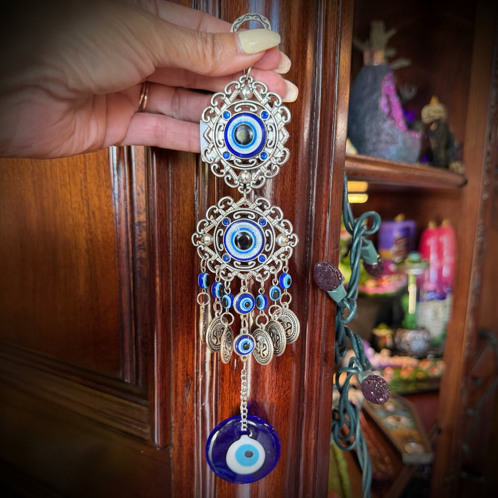 Hand holding two decorative brooches with blue and gold designs against a wooden background.