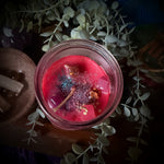 Close-up of a red candle in a glass jar with decorative elements on a dark background