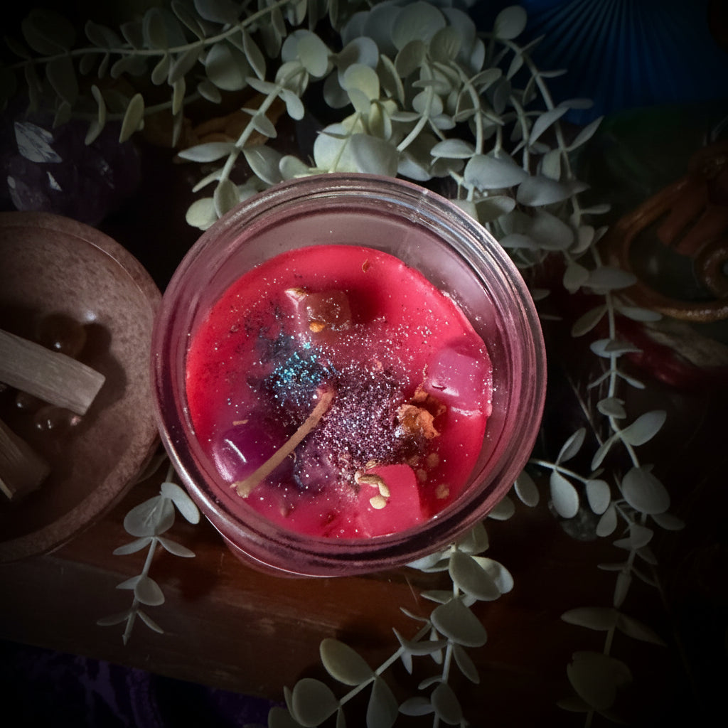 Close-up of a red candle in a glass jar with decorative elements on a dark background
