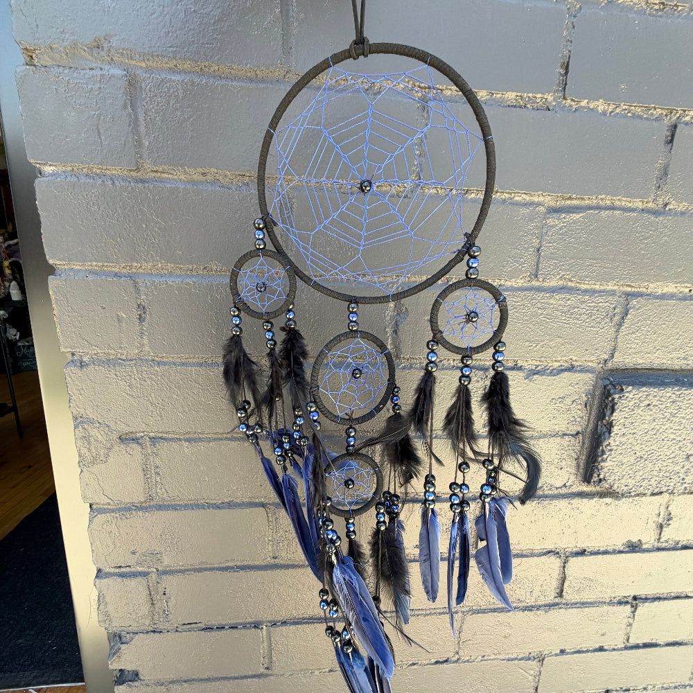Dreamcatcher with blue feathers hanging on a brick wall