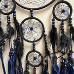 Black and blue dreamcatcher with feathers on a beige background