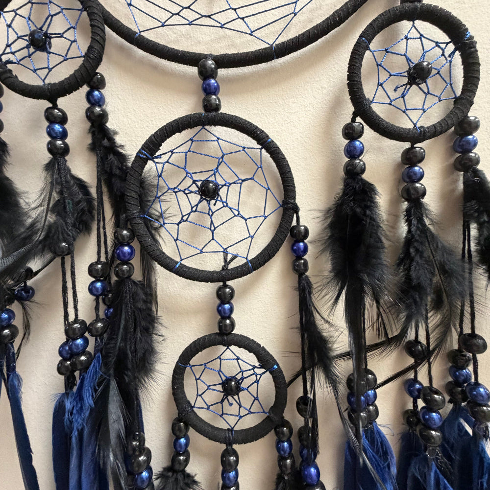 Black and blue dreamcatcher with feathers on a beige background