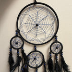 Black and blue dreamcatcher with feathers on a beige background