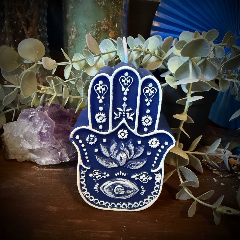 Decorative blue Hamsa hand with plants and a crystal on a wooden surface