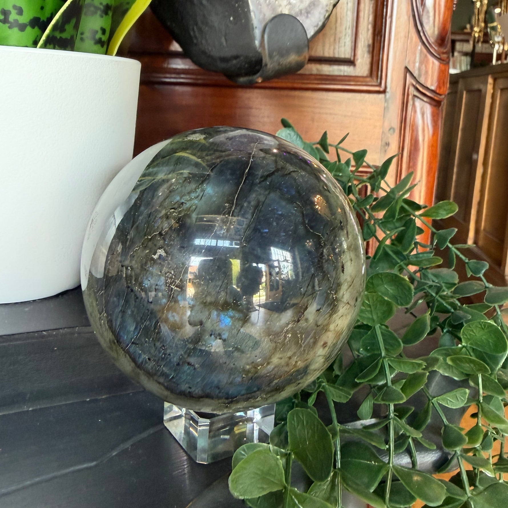 Crystal ball on a surface with plants and decorative items in the background