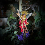 Decorative arrangement with angel figurine, candle, and flowers on a textured surface.