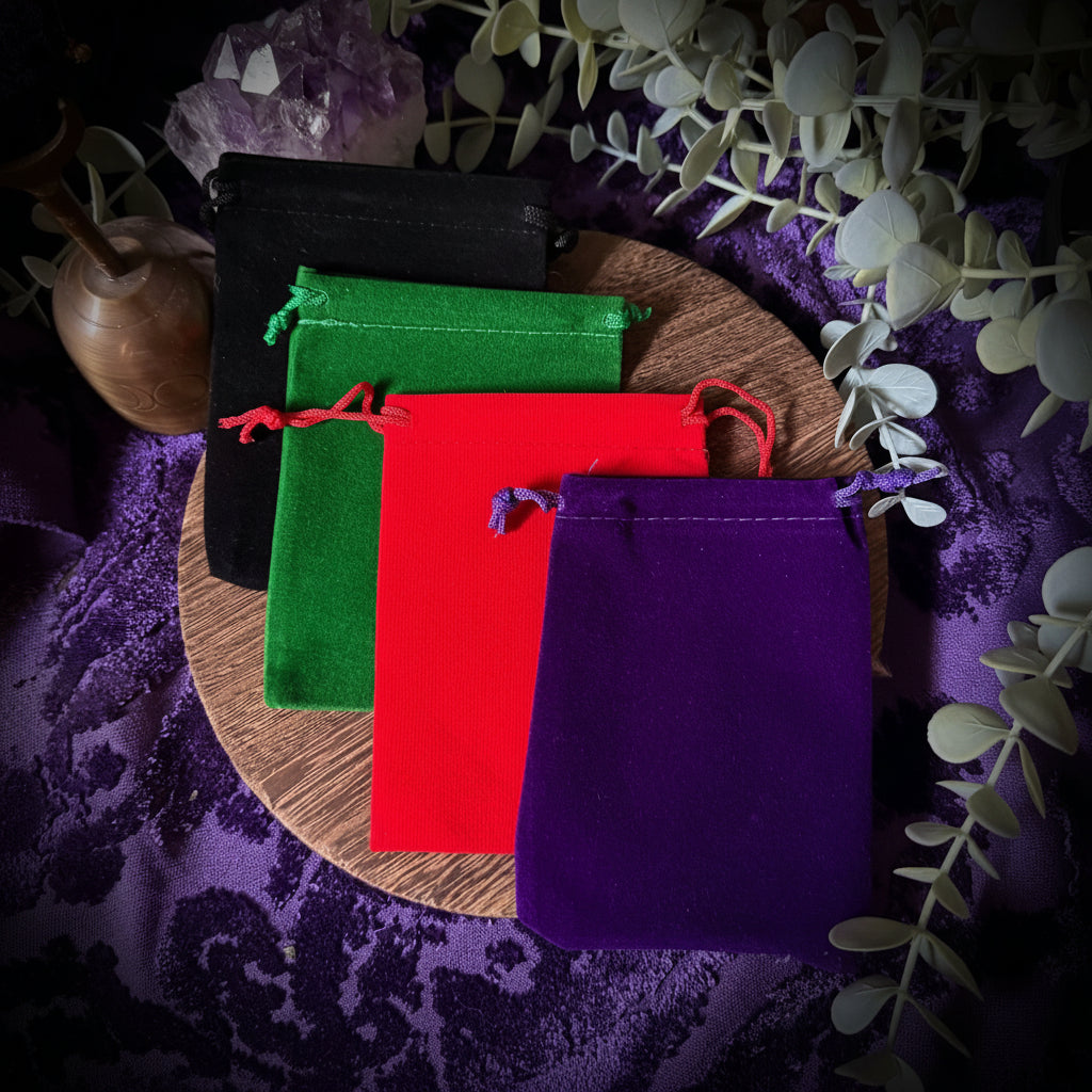 Colorful velvet bags on a wooden board with purple fabric and eucalyptus leaves in the background