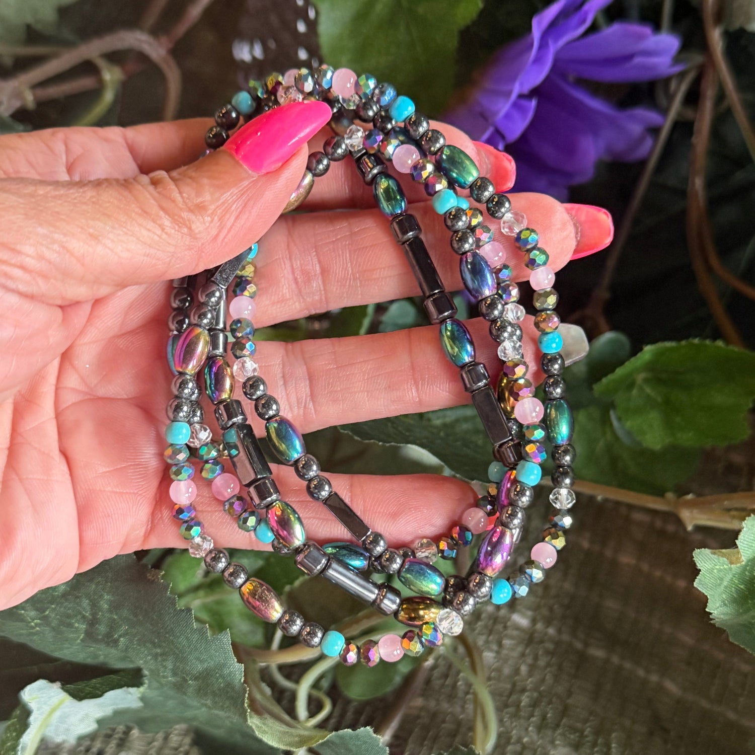 Multicolored beaded keychain held in a hand with pink nail polish against a natural background.
