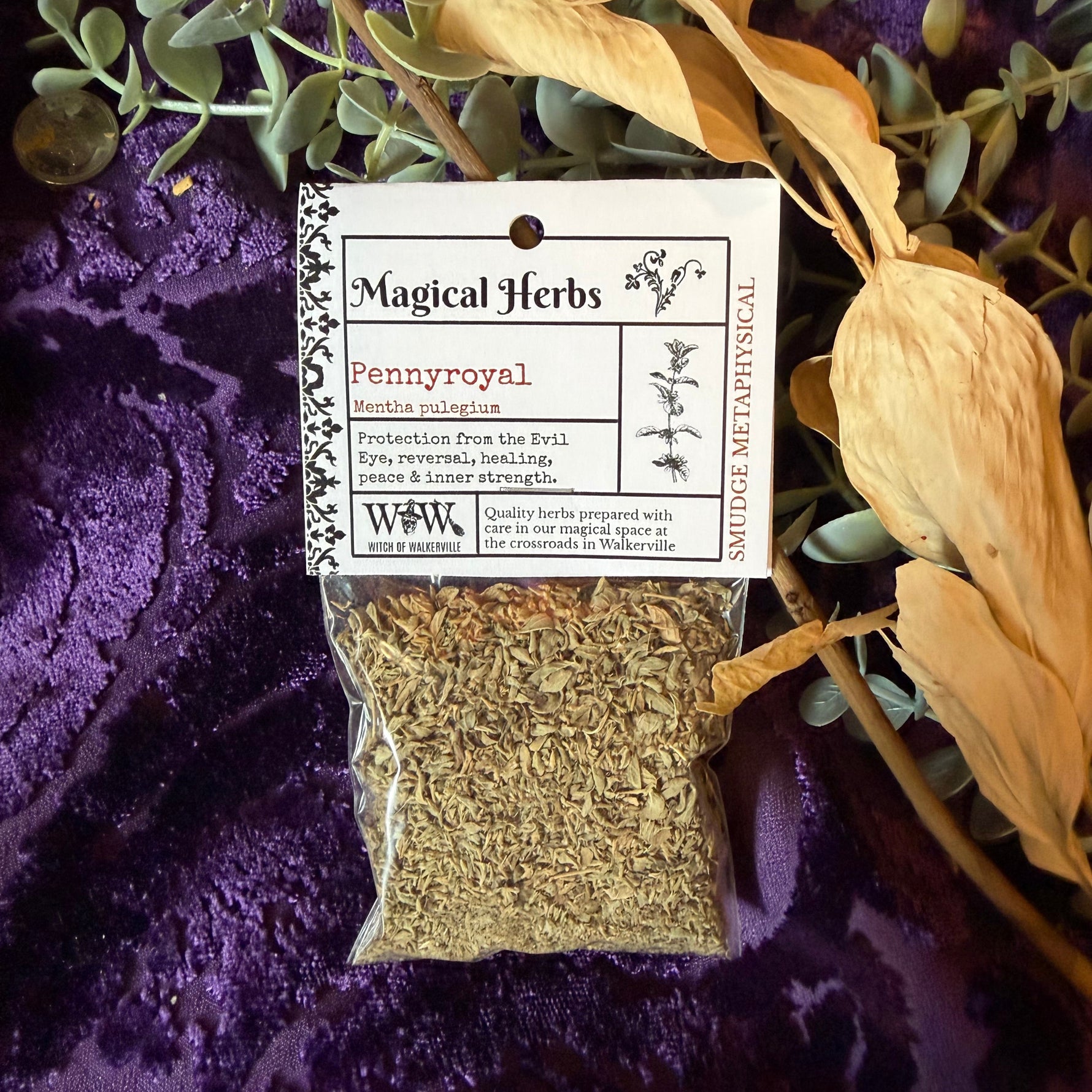 Herbal package labeled 'Magical Herbs' with dried herbs on a purple fabric background