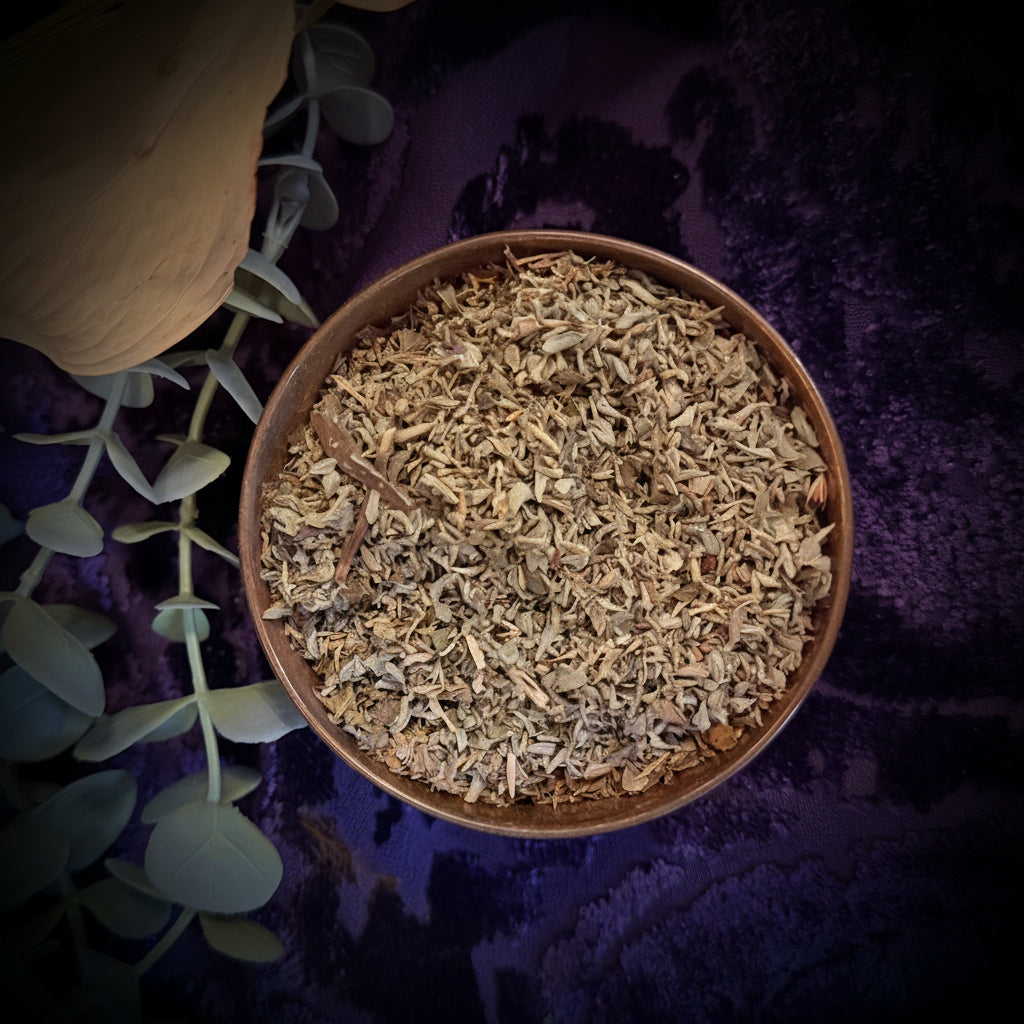 Small bowl of dried herbs on a textured purple surface with green leaves.