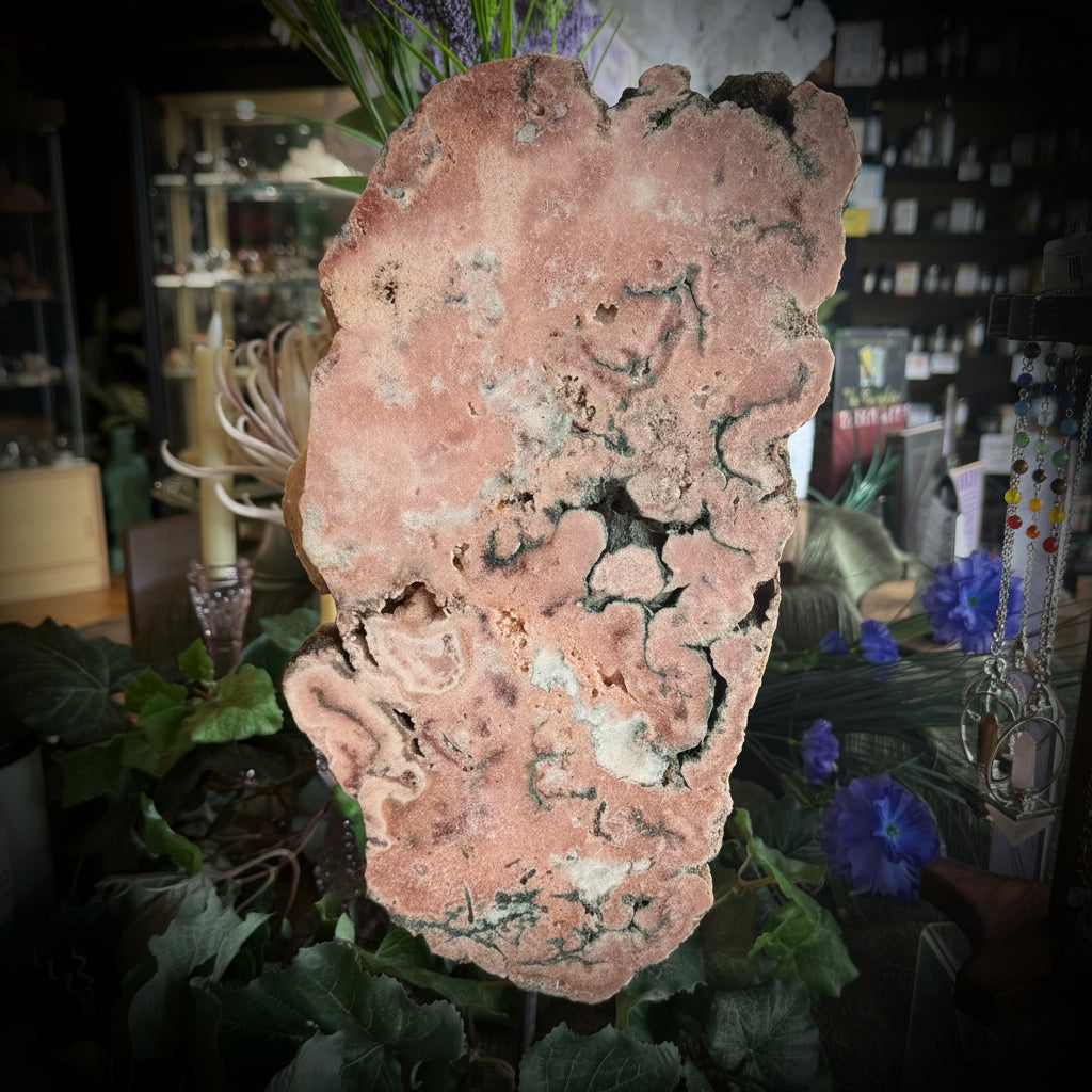 Large pink crystal on a stand with greenery in a store setting