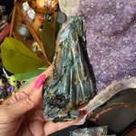 Green vivianite crystal being held by a hand.