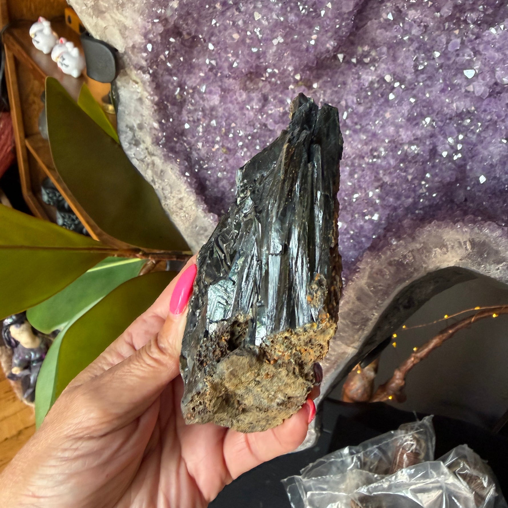 Person holding a crystal next to a purple crystal formation