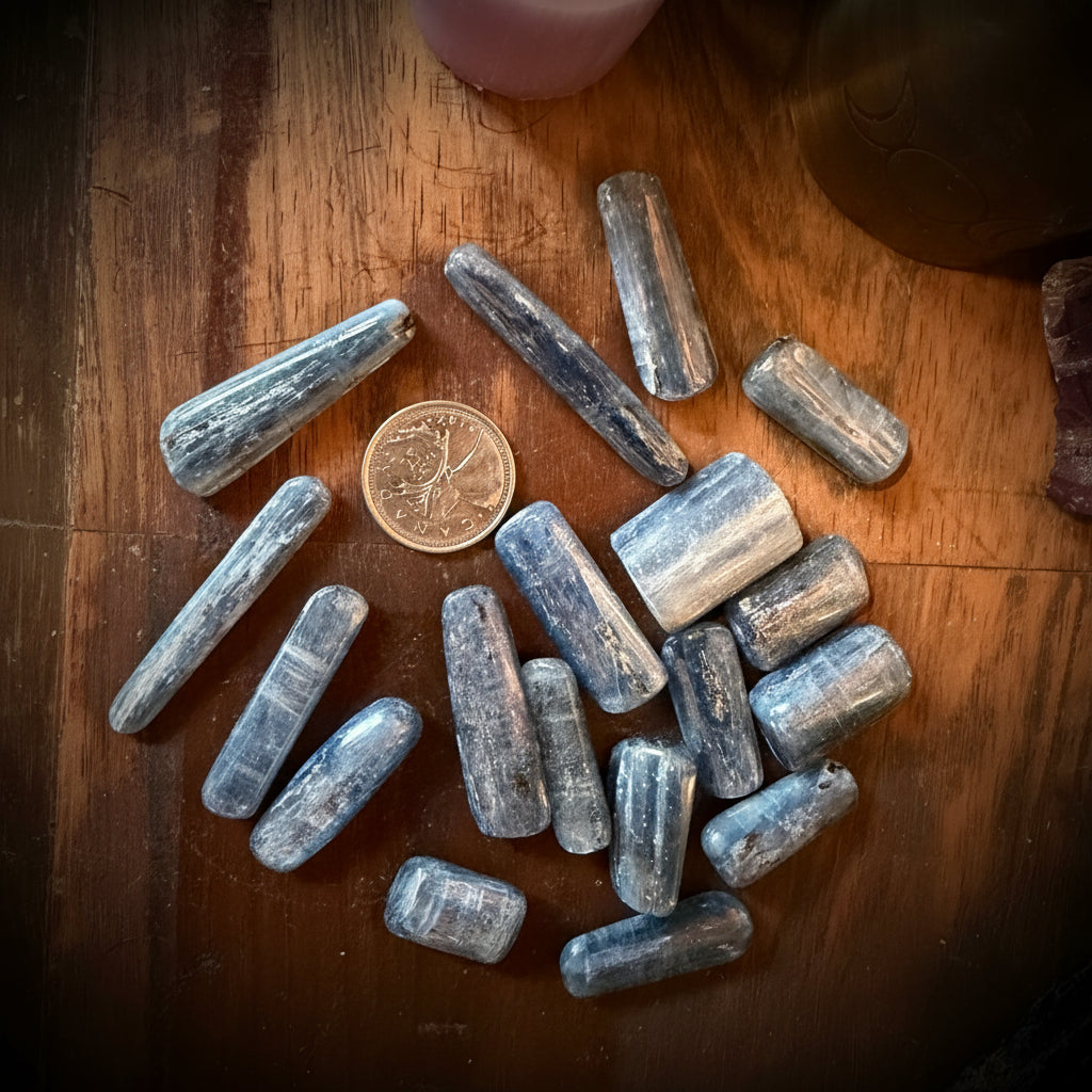 tumbled kyanite crystals on a wooden surface with a pink candle and decorative items.